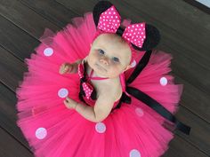 a baby girl wearing a pink and black minnie mouse tutu with polka dots on it