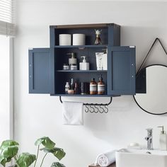 a bathroom with blue cabinets and white towels on the shelf next to it is a plant