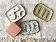 three soaps sitting on top of a white towel next to each other with different shapes and sizes