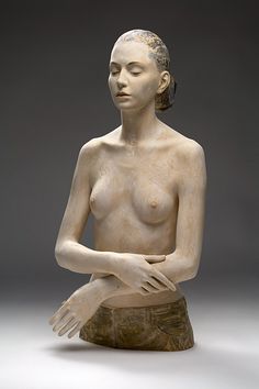 a statue of a woman sitting on top of a wooden block with her hands crossed