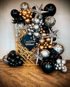 black, gold and silver balloons are on display in a basket with a sign that says celebration