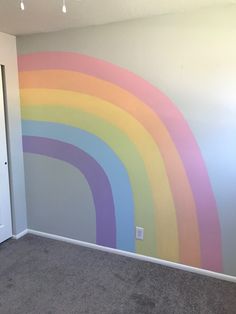 an empty room with a rainbow painted on the wall and carpeted flooring in front of it