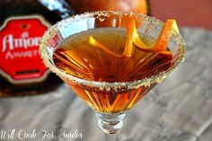 an alcoholic drink with orange peels in a martini glass on a table next to a bottle