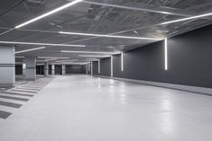 an empty parking garage with white floors and lights on the ceiling, in front of a black wall