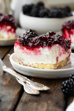 a piece of cheesecake on a white plate with berries in the background and silverware next to it