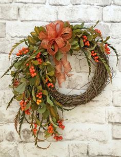 a wreath with an orange bow hanging on the side of a brick wall that says, happy