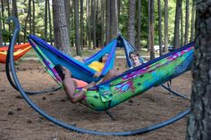 two people laying in hammocks in the woods