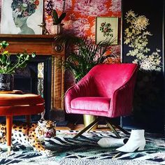 a pink chair sitting in front of a fire place next to a painting on the wall