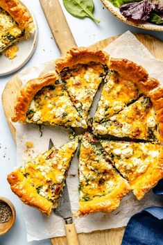 a quiche with cheese and spinach on a cutting board next to other dishes