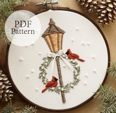 a cross stitch ornament with two birds on it and a light pole in the background