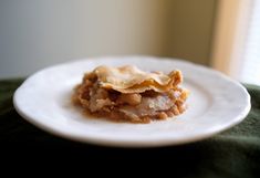 a piece of pie on a white plate sitting on a green table cloth next to a window