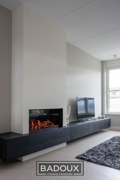 a living room with a television and fireplace in the center, next to a large window