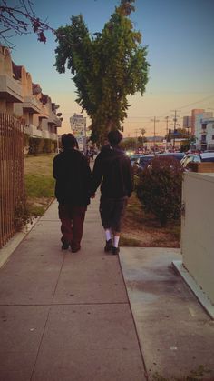 two people walking down a sidewalk holding hands