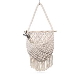 a white macrame bag hanging from a hook with tassels on it