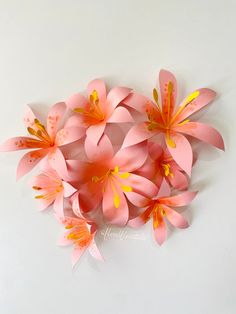 pink paper flowers are arranged on a white surface