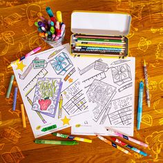 some crayons and markers are on the table next to coloring books, pencils and pens