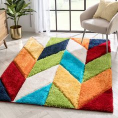 a colorful area rug in the middle of a room with a chair and potted plant