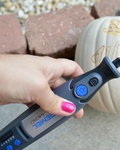 a person is holding a remote control in front of some pumpkins on the ground