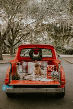 the back end of an orange truck with christmas decorations on it's bed and wreath