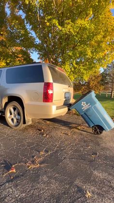 a silver suv parked on the side of a road next to a trash can and tree