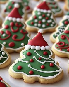 christmas cookies decorated with green and red icing are on a table in the shape of trees