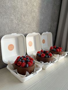 three trays with cake and berries on them sitting on a table next to each other