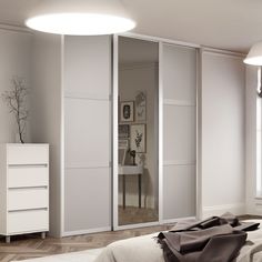 an empty bedroom with white furniture and large mirrors on the wall above the closet doors