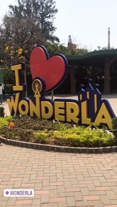 a sign that says i love wonderlandla in front of a park with flowers and trees