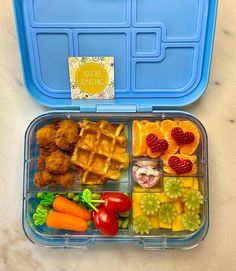 a blue lunch box filled with waffles, fruit and veggies