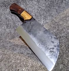 a knife with a wooden handle sitting on top of a gray carpeted flooring