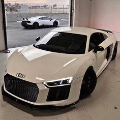 a white car parked in a garage next to two other cars