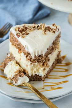 a slice of carrot cake with white frosting and nuts on top, sitting on a plate next to a fork