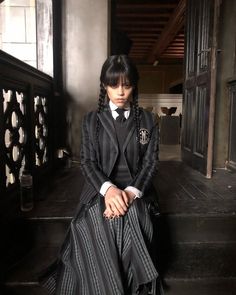 a woman sitting on steps wearing a black and white dress with long braids in her hair