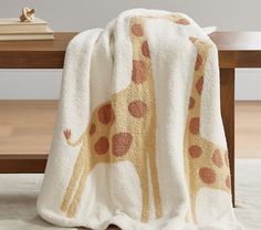 a giraffe blanket sitting on top of a table next to a wooden bench