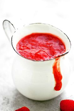 a small white pitcher filled with sauce and strawberries