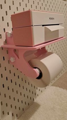 a pink and white box on top of a toilet paper dispenser