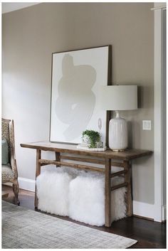 a living room with a table, chair and large poster on the wall above it