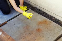 a person in yellow gloves and rubber gloves cleaning concrete