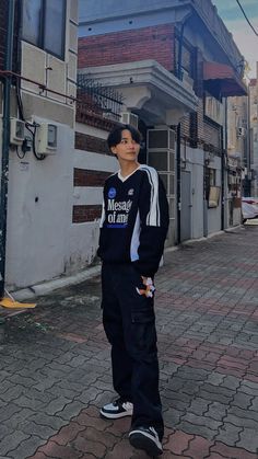 a young man standing on the sidewalk in front of a building