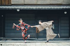 two people in kimonos are dancing on the street