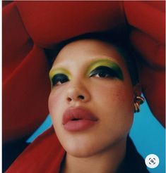 a woman with green eyeshades and red scarf on her head, wearing gold hoop earrings