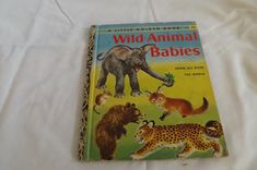 an old children's book about wild animal babies on a white bed sheet with the cover pulled down