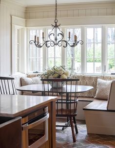 a dining room table with chairs and a chandelier hanging from the ceiling above it