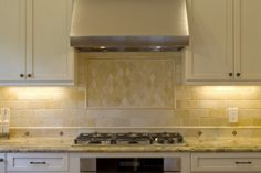 a stove top oven sitting inside of a kitchen next to white cabinets and counter tops