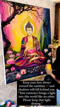 a woman sitting in front of a painting with flowers on it and a quote from buddha