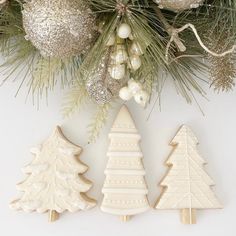 three decorated cookies sitting next to each other on top of a table with christmas decorations