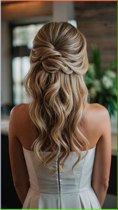 the back of a woman's head with long wavy hair in a half - updo