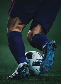 the legs and feet of a soccer player with a ball in his hand on a field