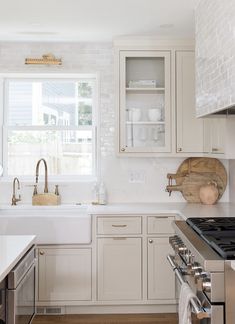 a kitchen with white cabinets and stainless steel appliances in the center, along with wooden cutting boards on the countertop