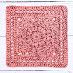 an orange crocheted square is shown on a white wooden surface with the words, granny